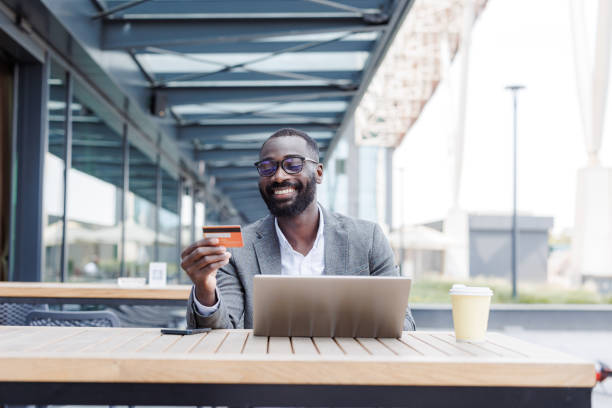 istock Businessman with laptop outdoors using a credit card at a cafe 2167779470