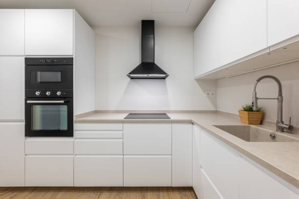 istock Modern kitchen with integrated appliances, black range hood, and white palette for a sleek space 2167780265