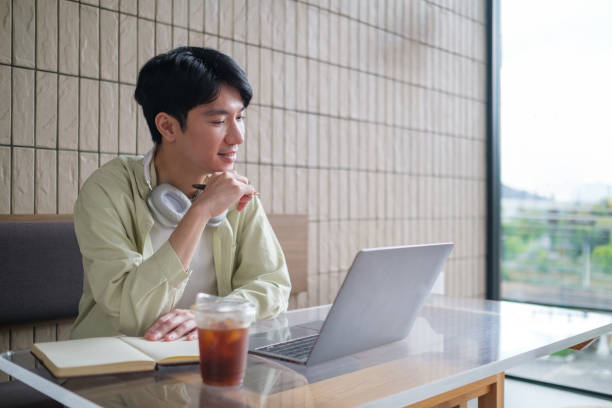 istock Young man is sitting at a modern cafe, focused on his laptop. 2167782001