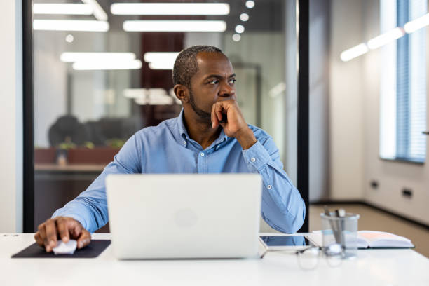 istock Thoughtful businessman working at modern office desk with laptop and notebook 2167782551