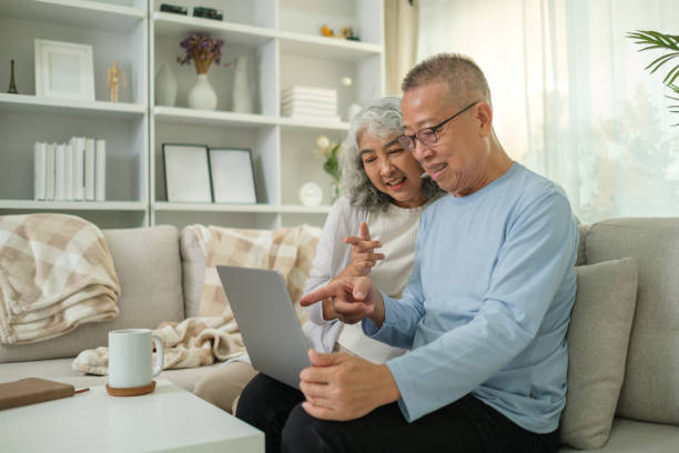 istock Loving elderly couple using laptop while sitting together on a cozy sofa in a bright living room. 2167782657