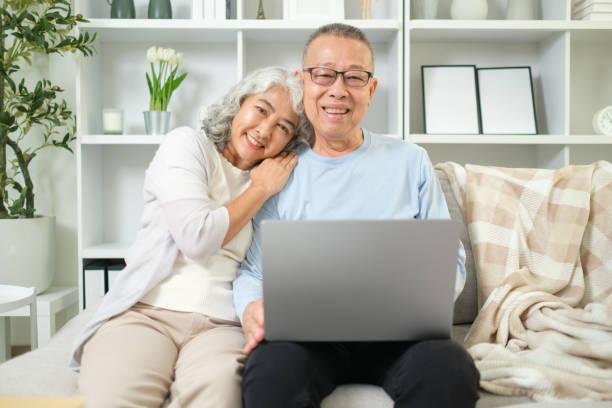 istock Affectionate elderly couple sitting closely together on a comfortable sofa with laptop. 2167782699