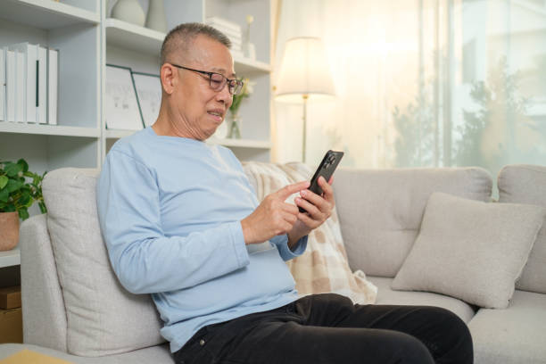 istock Smiling mature man using mobile phone on a sofa in cozy living room. 2167782726