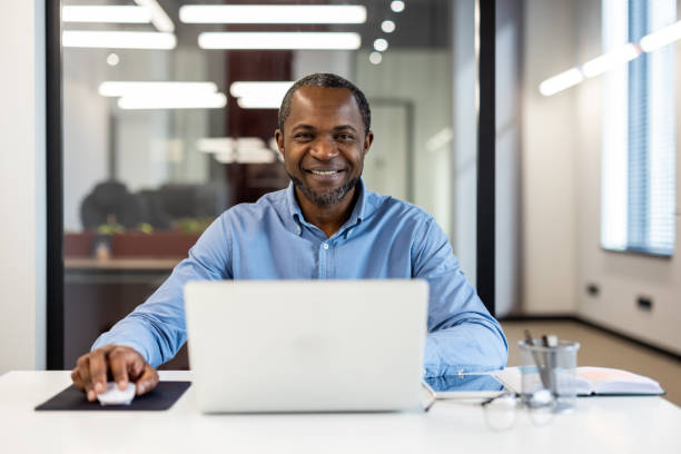 istock Smiling businessman at desk working on laptop in modern office 2167782808