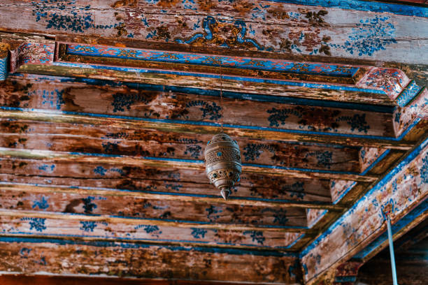 A lantern hangs from the ceiling of a room with a blue and brown ceiling. The lantern is hanging from a wooden beam