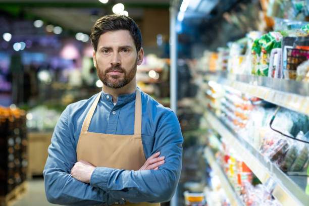 istock Confident grocery store worker standing in aisle with crossed arms 2167788157