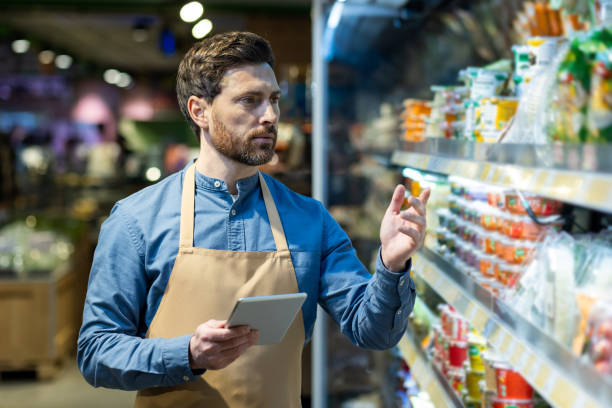 istock Supermarket employee using tablet to manage inventory while checking products on shelves 2167788360
