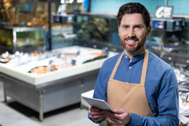 istock Smiling fishmonger holding tablet in modern seafood market 2167790828