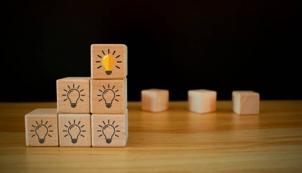 istock Team creative idea or innovative idea concept, Brainstorming process, Wooden blocks with question mark head icon stacked in pyramid stair shape and the top one with light bulb. 2167791211