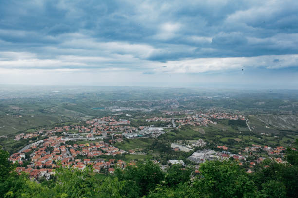 A sweeping view of San Marino reveals its charming rooftops and rolling hills against a dramatic, overcast sky.