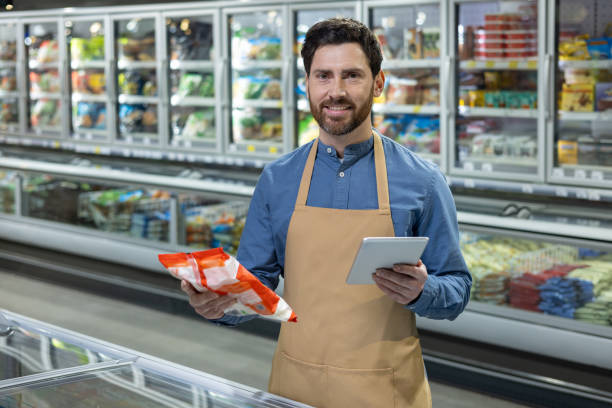 istock Supermarket worker holding frozen food package while using digital tablet 2167794557