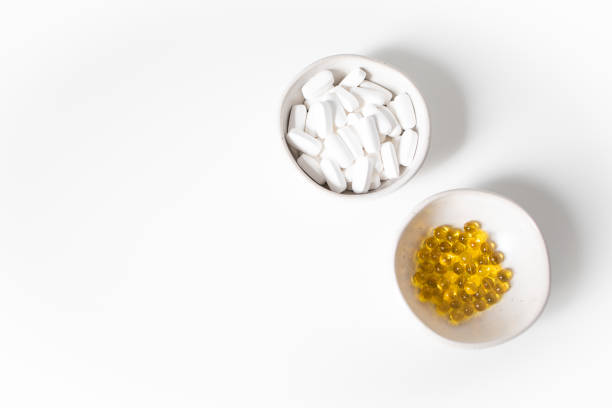 White and yellow pills in small bowls on a white background