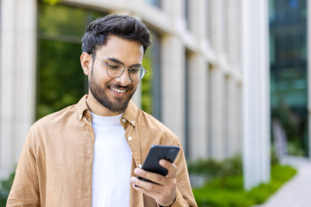 istock Smiling man using smartphone outdoors near modern building on sunny day 2167800841