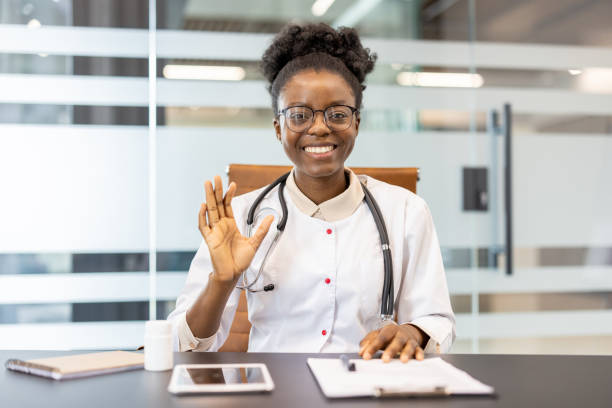istock Smiling doctor waving during online video call in modern office setting 2167800876