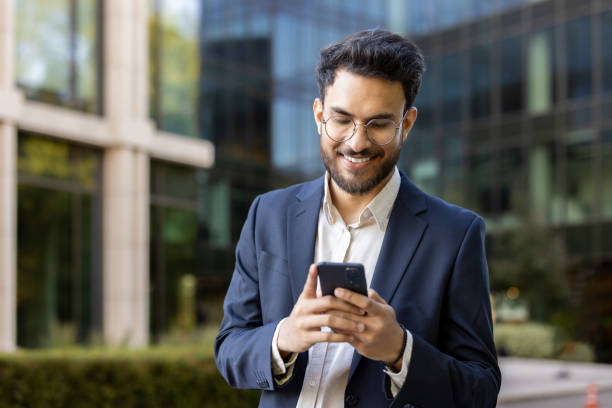 istock Smiling businessman using smartphone outside modern office building 2167801633