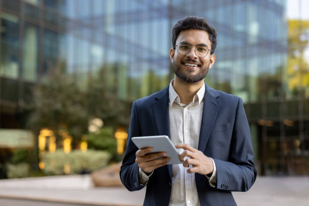 istock Confident young businessman using tablet outside modern office building 2167802327