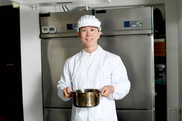 istock An Asian man wearing a white coat (cooking clothes) is holding a pot in the kitchen. 2167803281