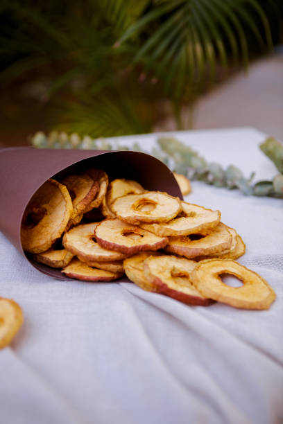 Single slice of dry green apple sprinkled with cinnamon powder isolated on white background. Dehydrated chip snack