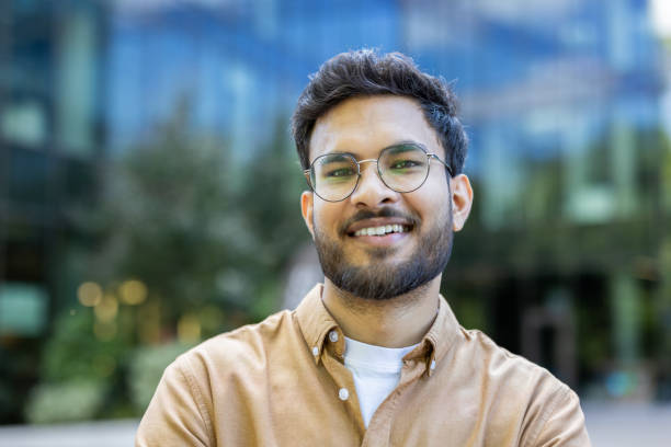 istock Smiling young man with glasses standing outdoors in front of modern building 2167804806