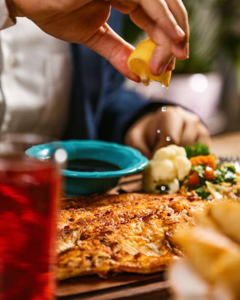 Businessman is squeezing a lemon on a delicious fish dish in a restaurant