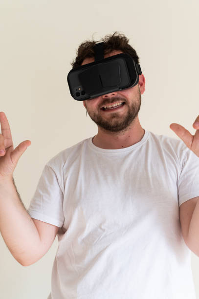 Man is wearing virtual reality glasses and interacting with the virtual world, smiling and gesturing with his hands
