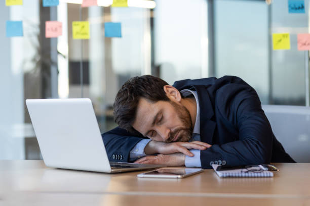 istock Tired businessman sleeping at desk in office with laptop and documents around 2167809072