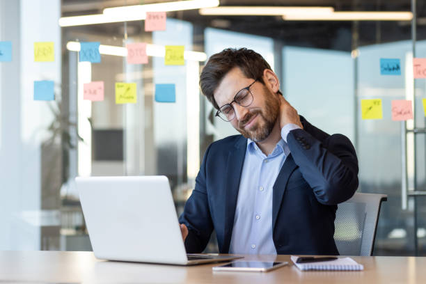 istock Businessman experiencing neck pain while working at desk in modern office 2167810747