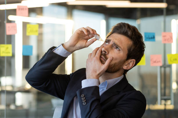 istock Businessman applying eye drops in modern office setting with sticky notes in background 2167811276