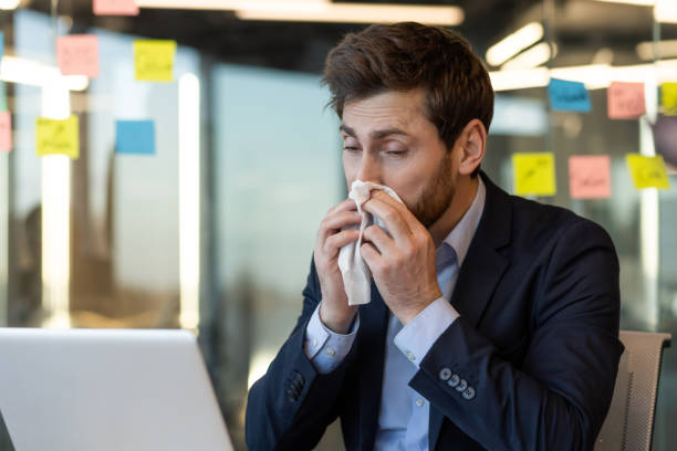 istock Businessman working with laptop suffering from cold and using tissue 2167811500