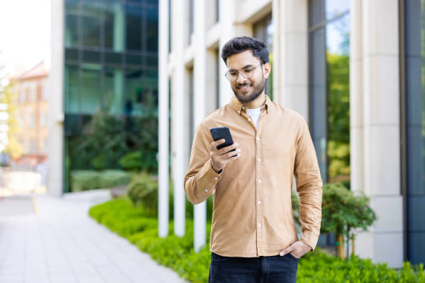 istock Hispanic man using smartphone outside modern office building in daylight 2167812145