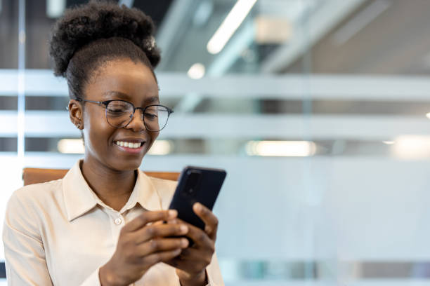 istock Young African American businesswoman smiling while using smartphone at workplace 2167812701