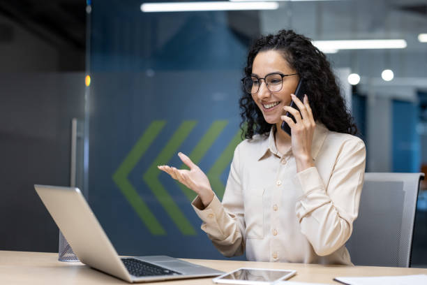 istock Young businesswoman smiling while talking on phone in modern office setting 2167815264