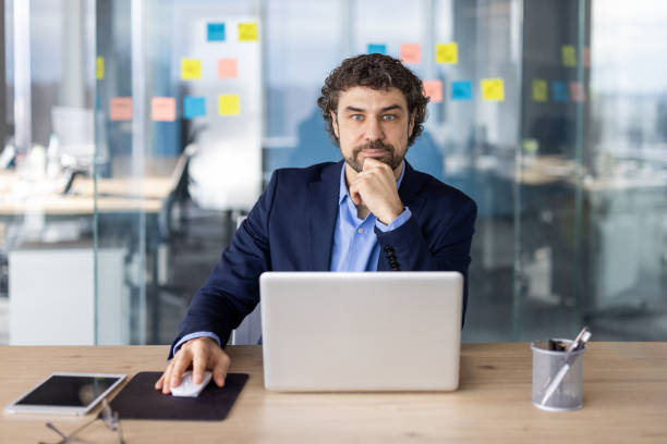 istock Confident businessman working at desk in office with laptop and thoughtful expression 2167816191