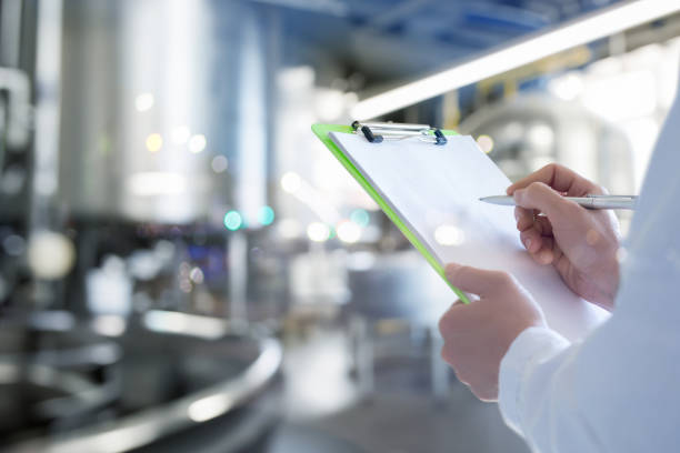 An engineer in a production facility makes entries in a journal. An engineer in a food production facility makes entries in a journal. Work as an engineer in a food company. product review stock pictures, royalty-free photos & images