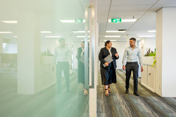 Young office workers chatting while walking through a modern office building