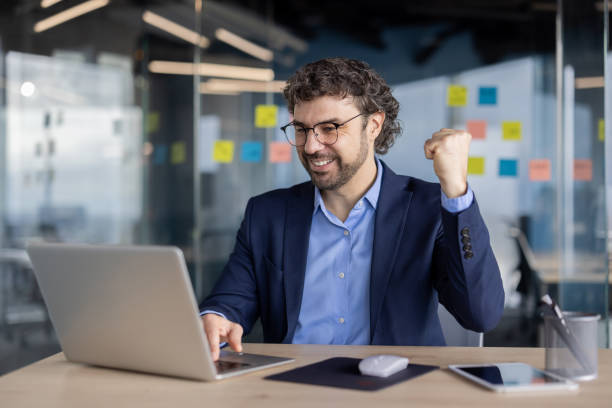 istock Businessman celebrating success at work in modern office with computer 2167818606
