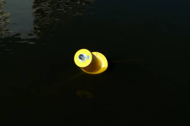 Yellow buoy floating on dark water with reflections. Copy space.