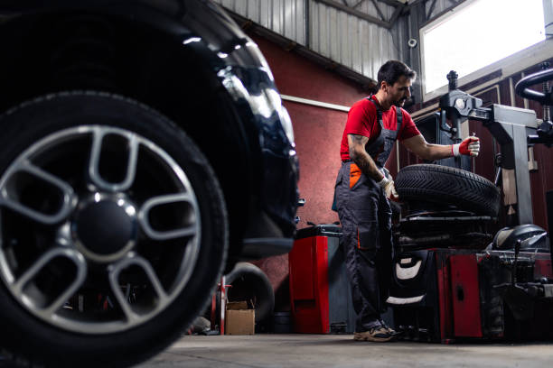 istock Hardworking man repairing punctured and damaged tire in workshop. 2167820950