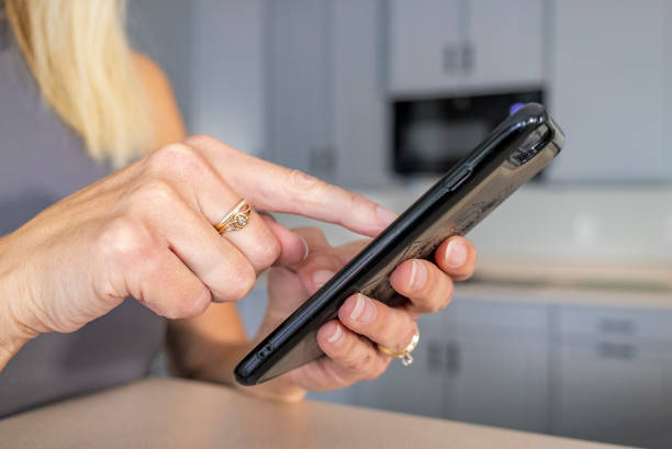 istock Close Up of Female Hand Using a Smart Phone in the Kitchen 2167822840