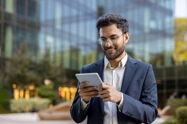 istock Smiling businessman using a digital tablet outside modern office building 2167822939