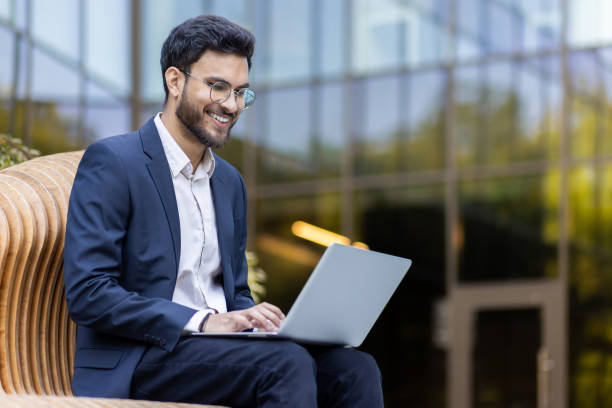 istock Smiling businessman working on laptop outdoors in modern urban setting 2167824125