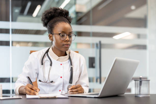 Focused doctor working on laptop and taking notes in modern medical office