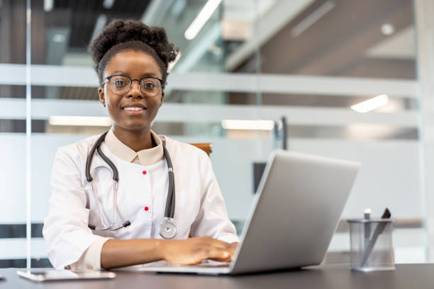 istock Friendly female doctor working on laptop smiling in bright modern office 2167826203