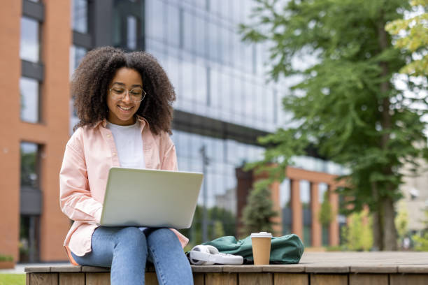istock Young female student using laptop near university campus on a sunny day 2167826296