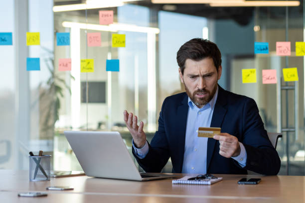 istock Businessman confused while checking credit card information at desk with laptop and notes in modern office environment 2167828262