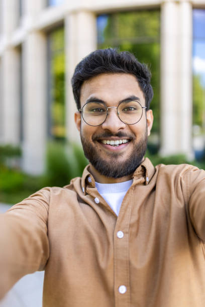 istock Cheerful hispanic man taking selfie outside office building on sunny day 2167828415