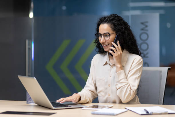 istock Professional woman working on laptop in office while talking on phone 2167828541