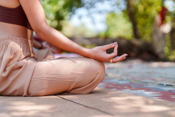 A mid-adult woman is seen engaging in a private moment of self-care and spiritual practice on a grassy lawn. Her eyes are closed, signifying deep concentration and inner peace. This image represents themes of balance, personal growth, self-reflection, and taking time for oneself away from the hustle of daily life.
