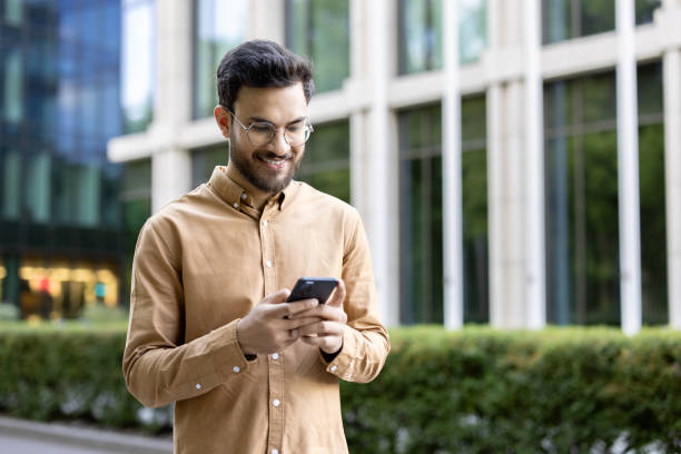 istock Young professional using smartphone in modern outdoor setting, smiling 2167830669