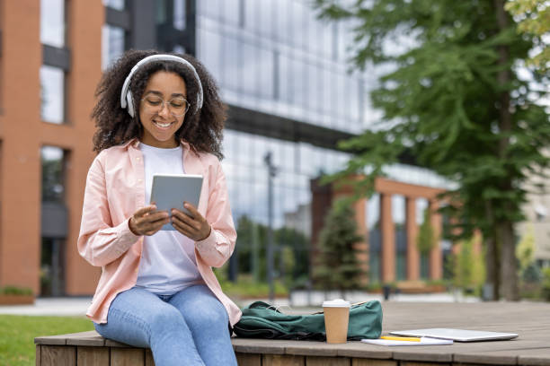 istock Young female student using tablet while sitting near university campus 2167831769